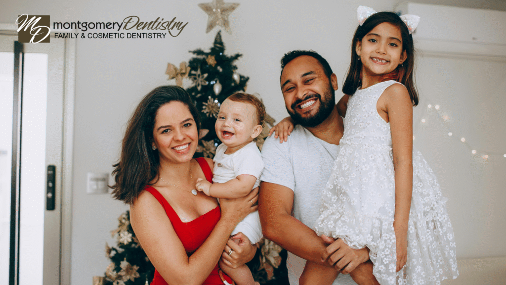Smiling family of four standing in front of Christmas tree