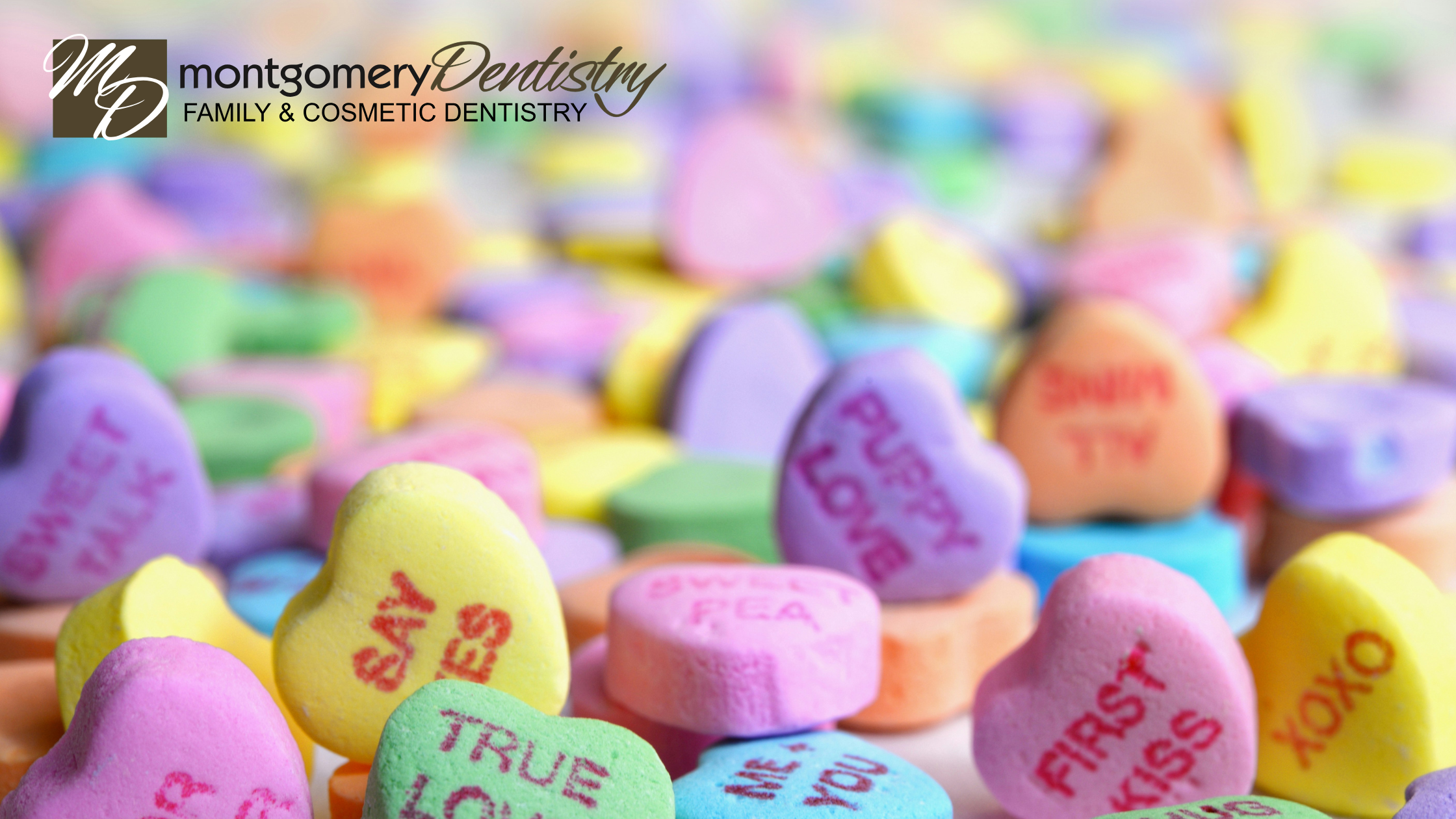 Close-up of candy Valentine hearts with Montgomery Dentistry logo in the top left corner