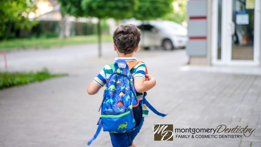 Little boy running while wearing a blue backpack. Montgomery Dentistry logo on bottom right corner.